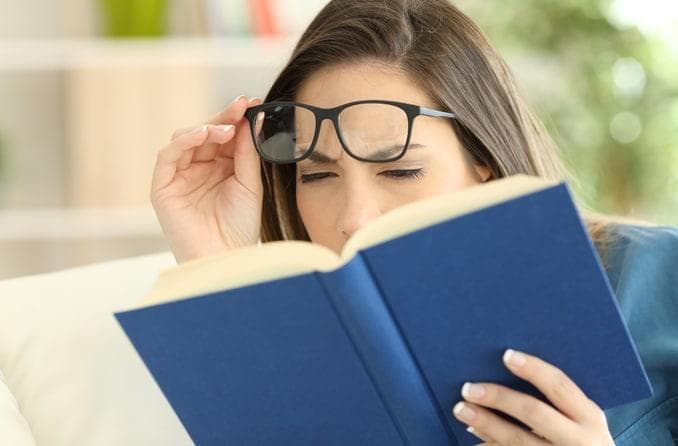 Woman experiencing reading difficulty and vision strain while using glasses